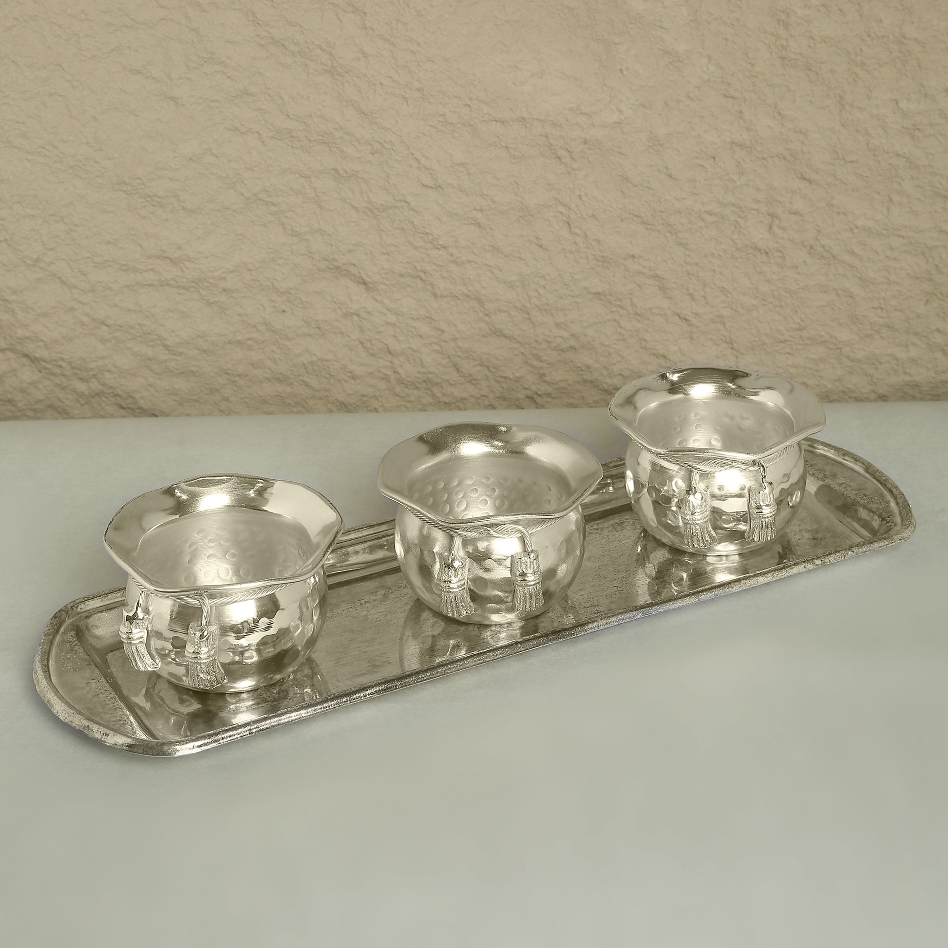 Set of silver tea cups and tray on a neutral background