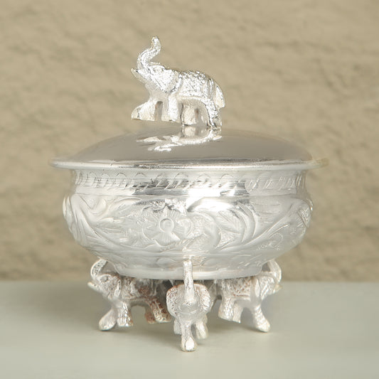 Decorative silver container with elephant design on a beige background