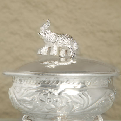 Silver container with an elephant on top against a beige background
