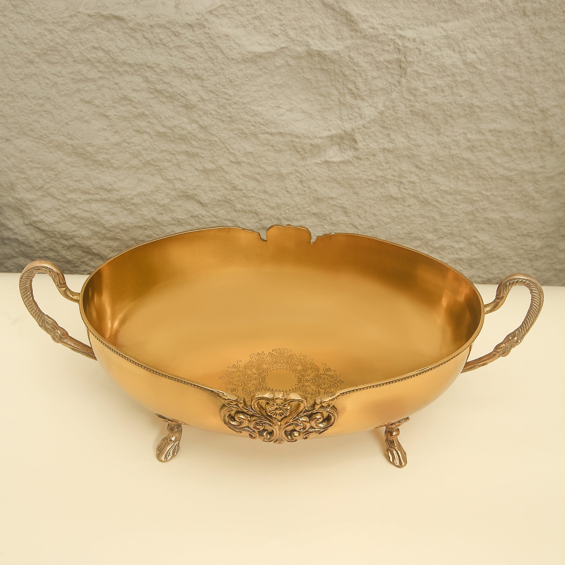Gold ornate bowl with handles on a light background