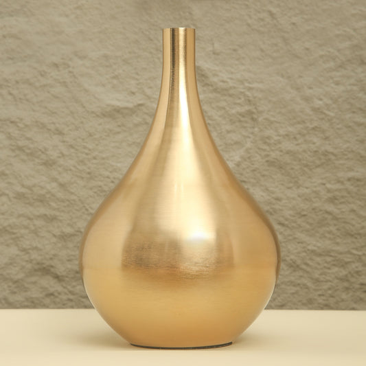 Gold vase on a beige surface with a textured brown wall background