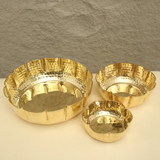 Three gold bowls with textured surfaces on a neutral background
