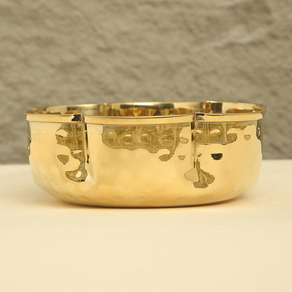 Gold bowl with engraved designs on a neutral background