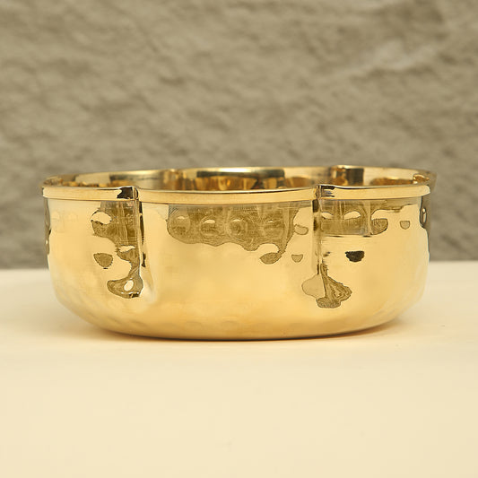 Gold bowl with engraved designs on a neutral background