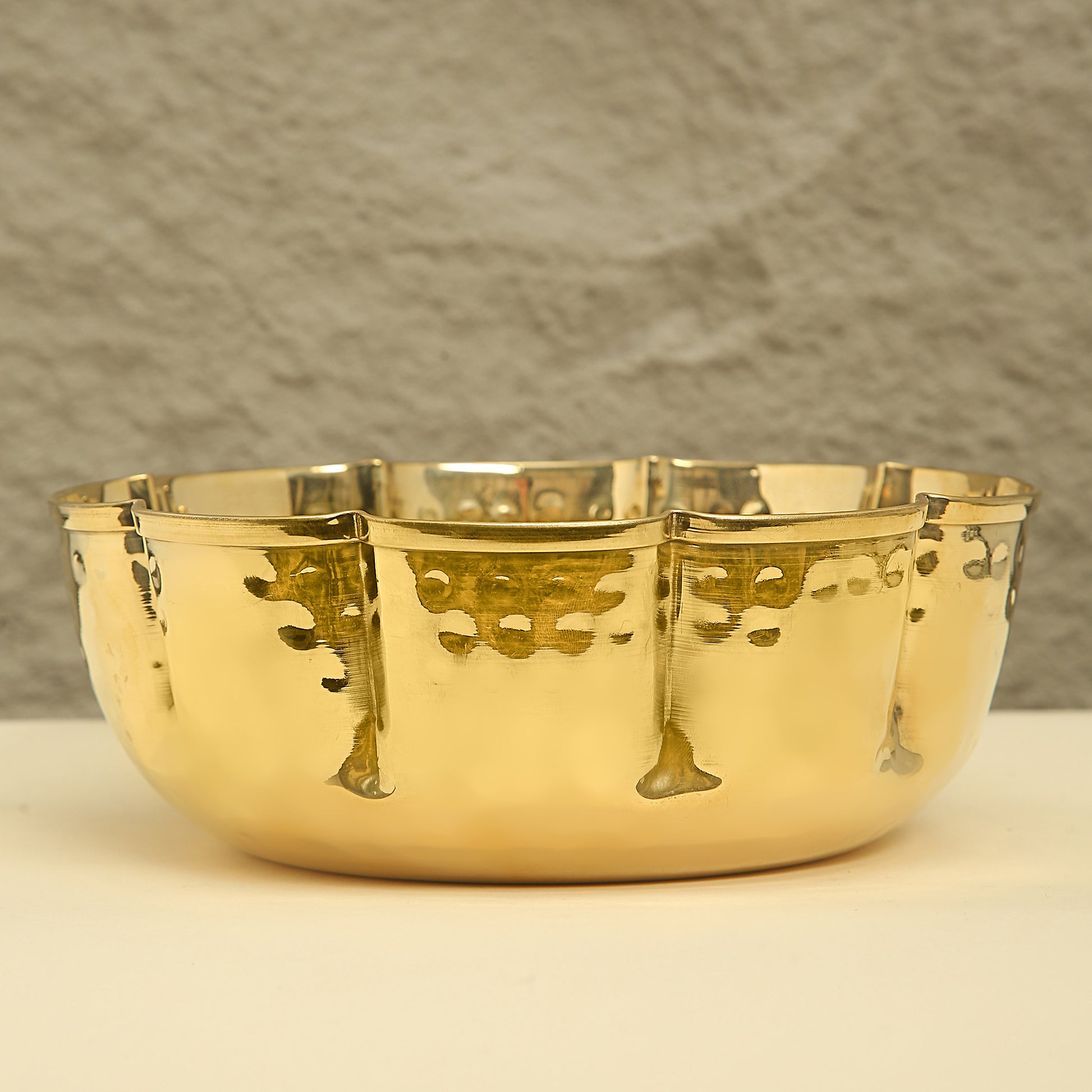 Gold decorative bowl with intricate designs on a neutral background