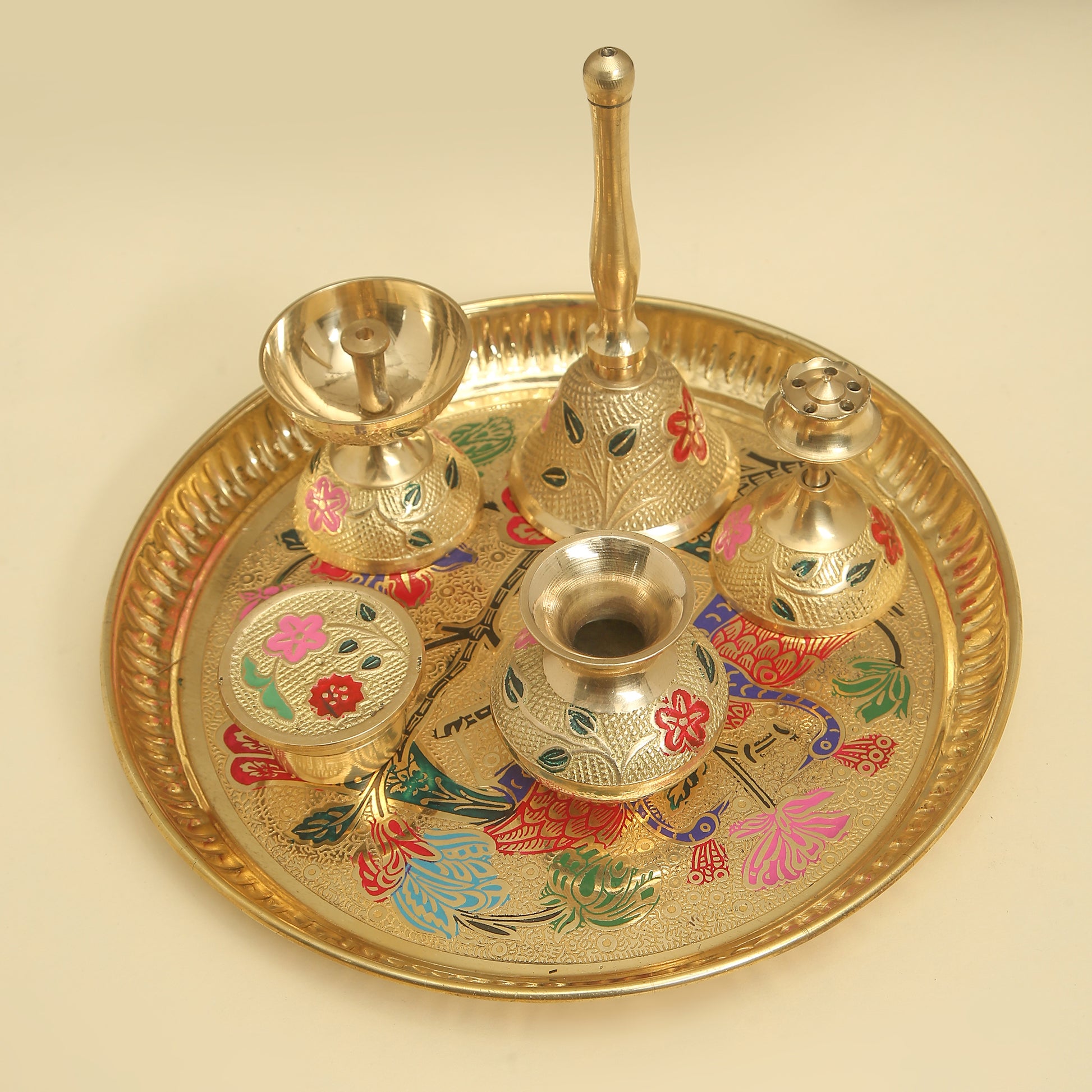Decorative brass tray with floral designs and multiple small pots on a beige background