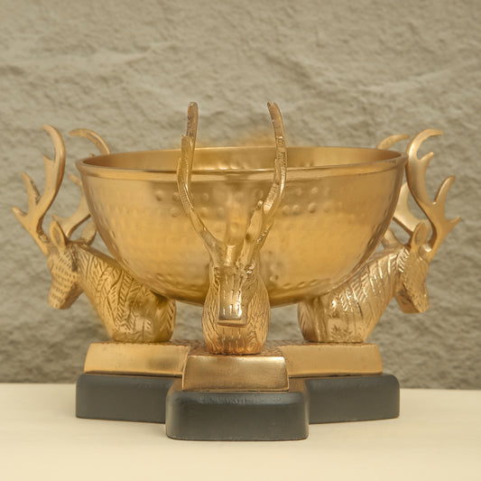 Gold bowl with deer head sculptures on a neutral background