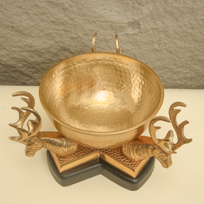 Gold bowl with deer head designs on a stone background