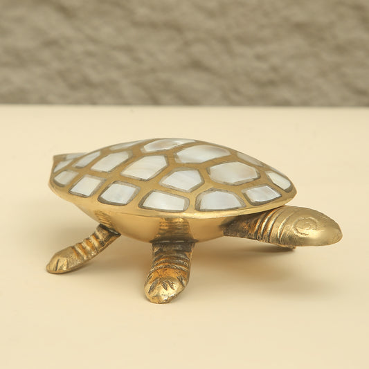 Brass turtle figurine with a checkered shell on a beige background