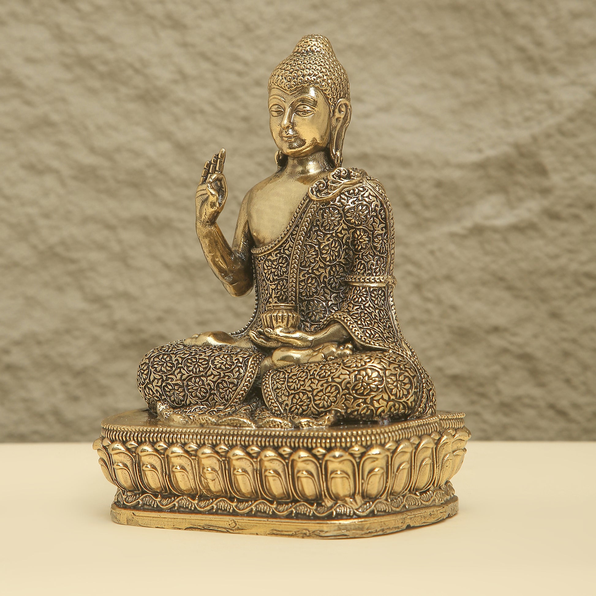 Bronze statue of a seated Buddha with intricate details on a textured background