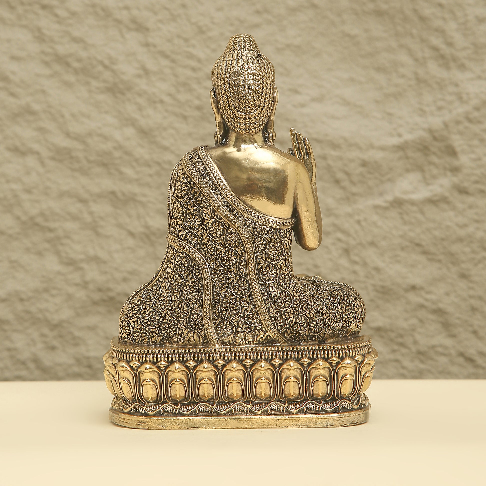 Bronze Buddha statue with intricate designs on a textured background
