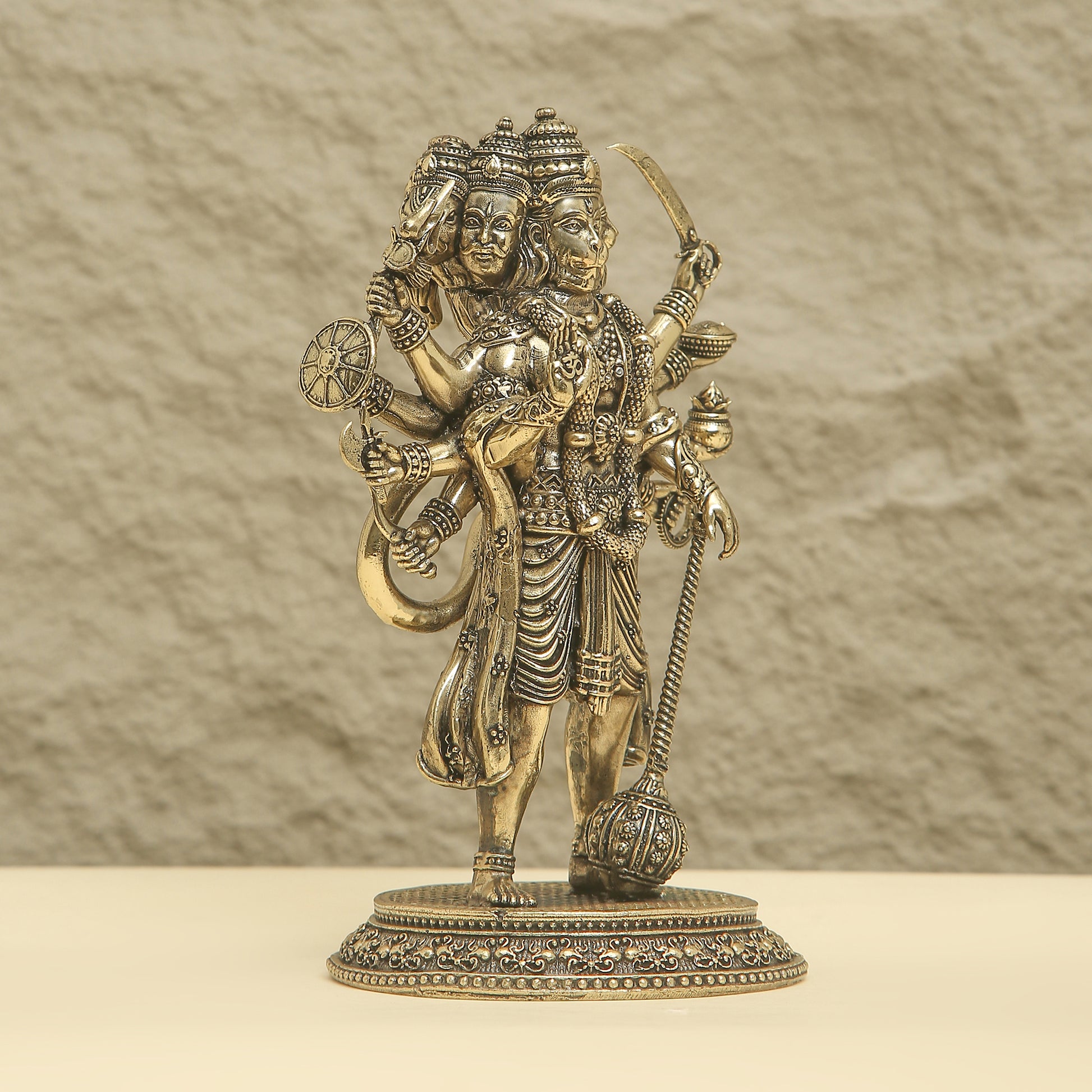 Bronze statue of a deity with intricate details on a beige background