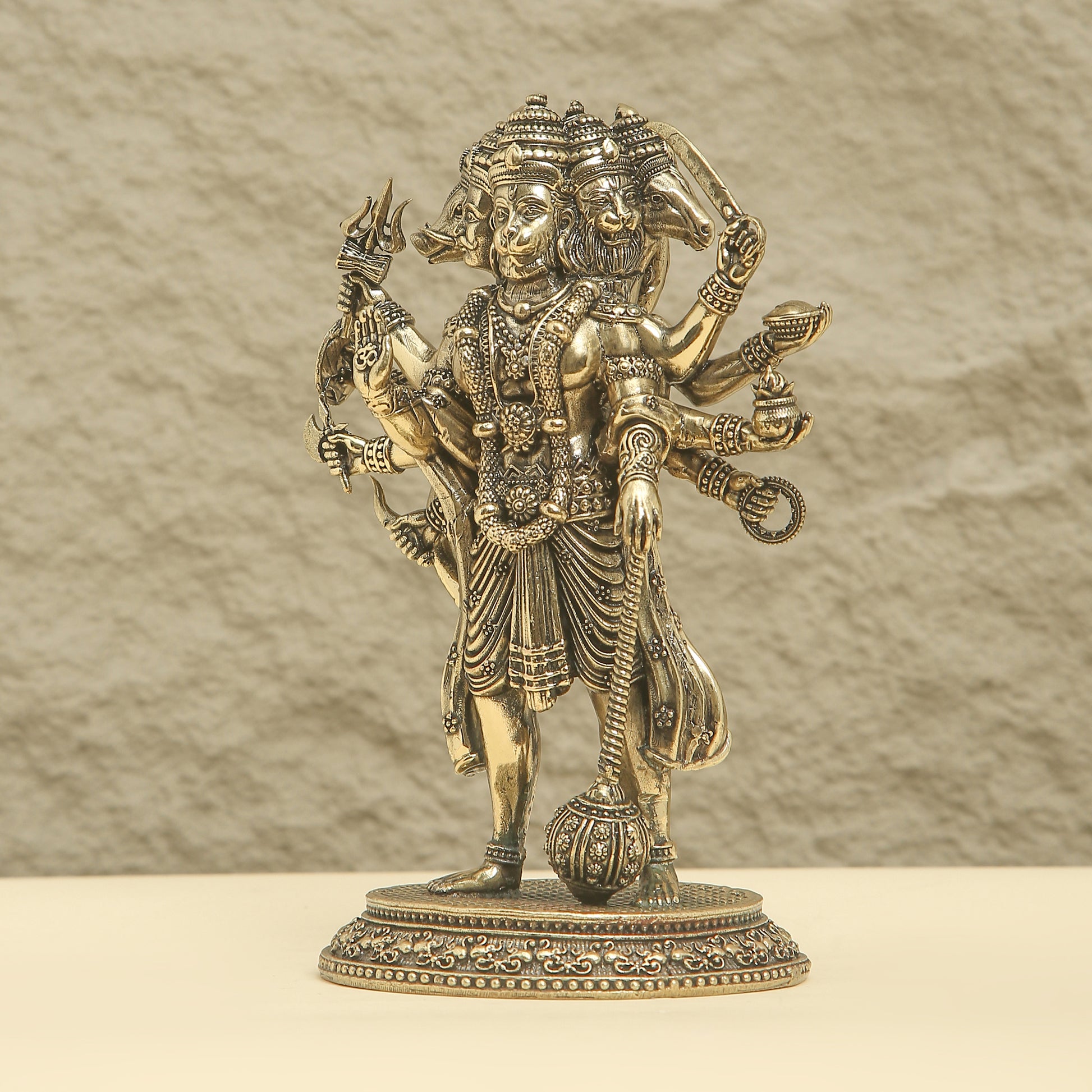 Bronze statue of a deity with multiple arms and weapons on a beige background