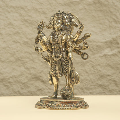 Bronze statue of a deity with multiple arms and weapons on a beige background