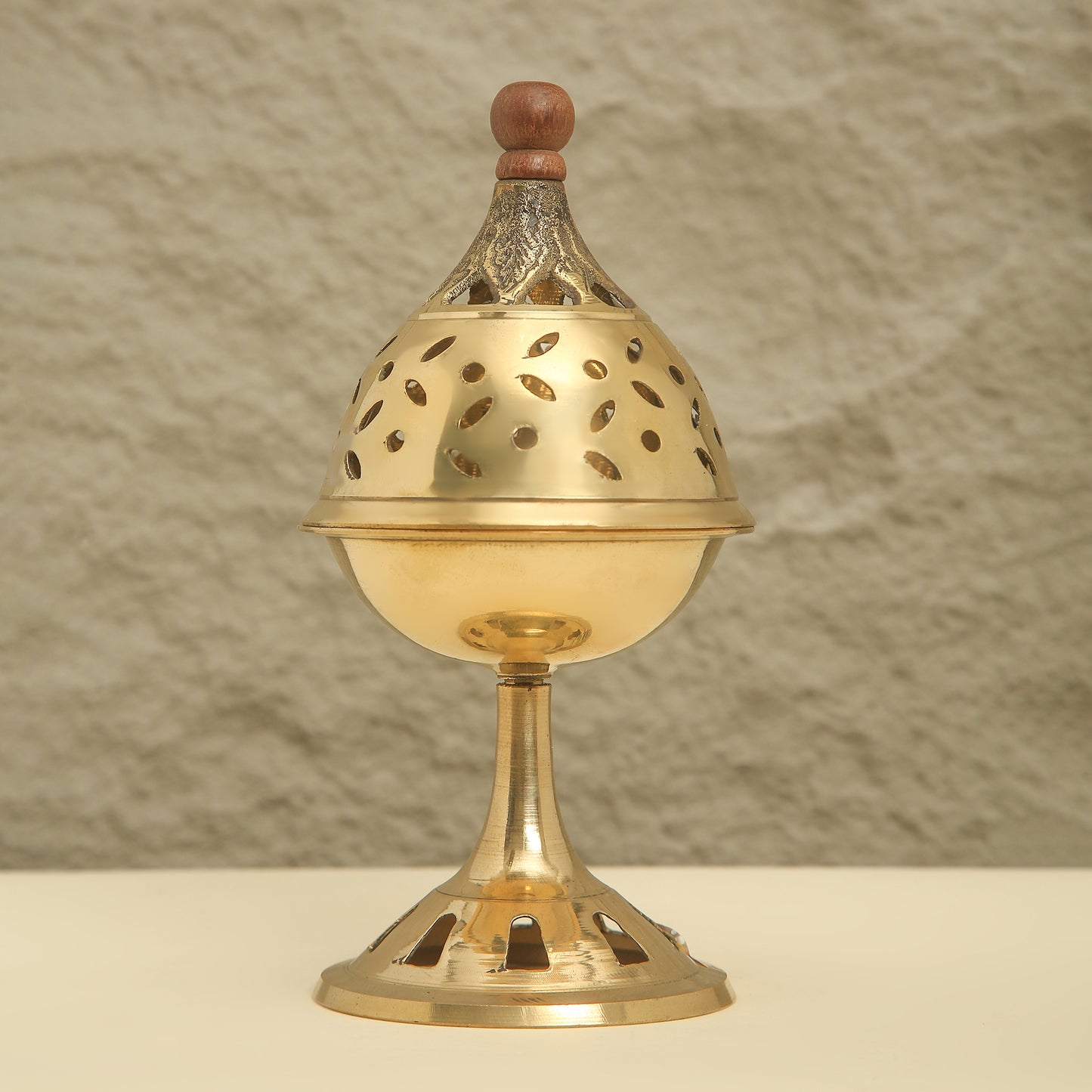 Brass incense burner with wooden top on a neutral background