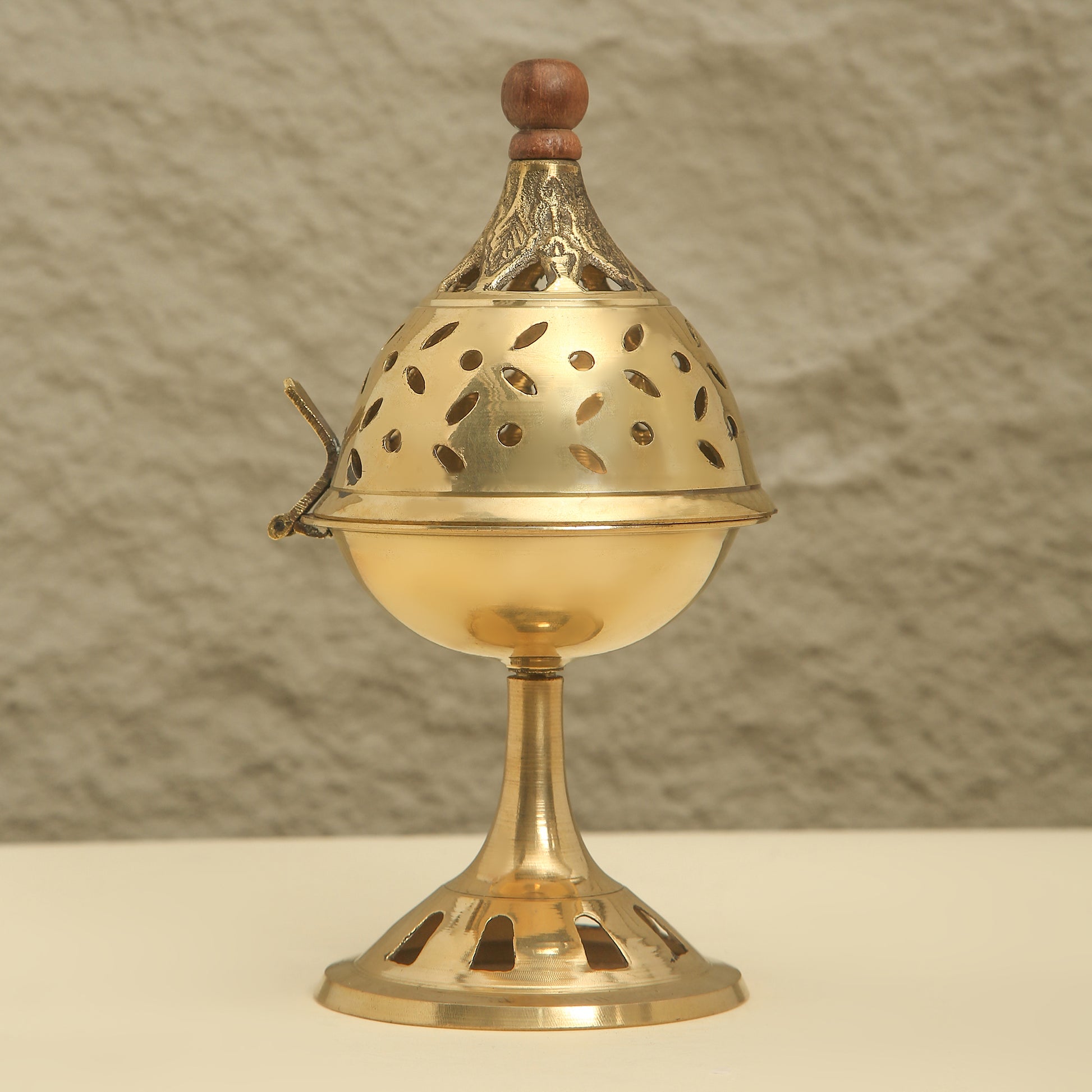 Brass incense burner with wooden top on a neutral background