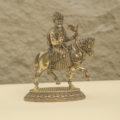 Bronze statue of a warrior on horseback with intricate details against a beige background