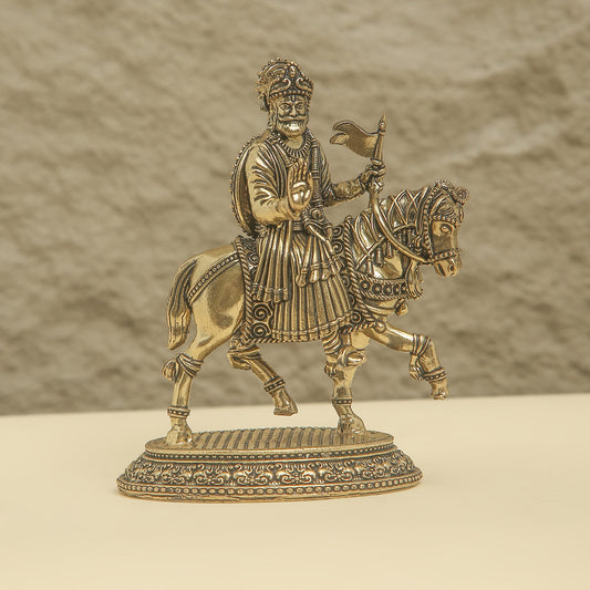 Bronze statue of a warrior on horseback with intricate details against a beige background