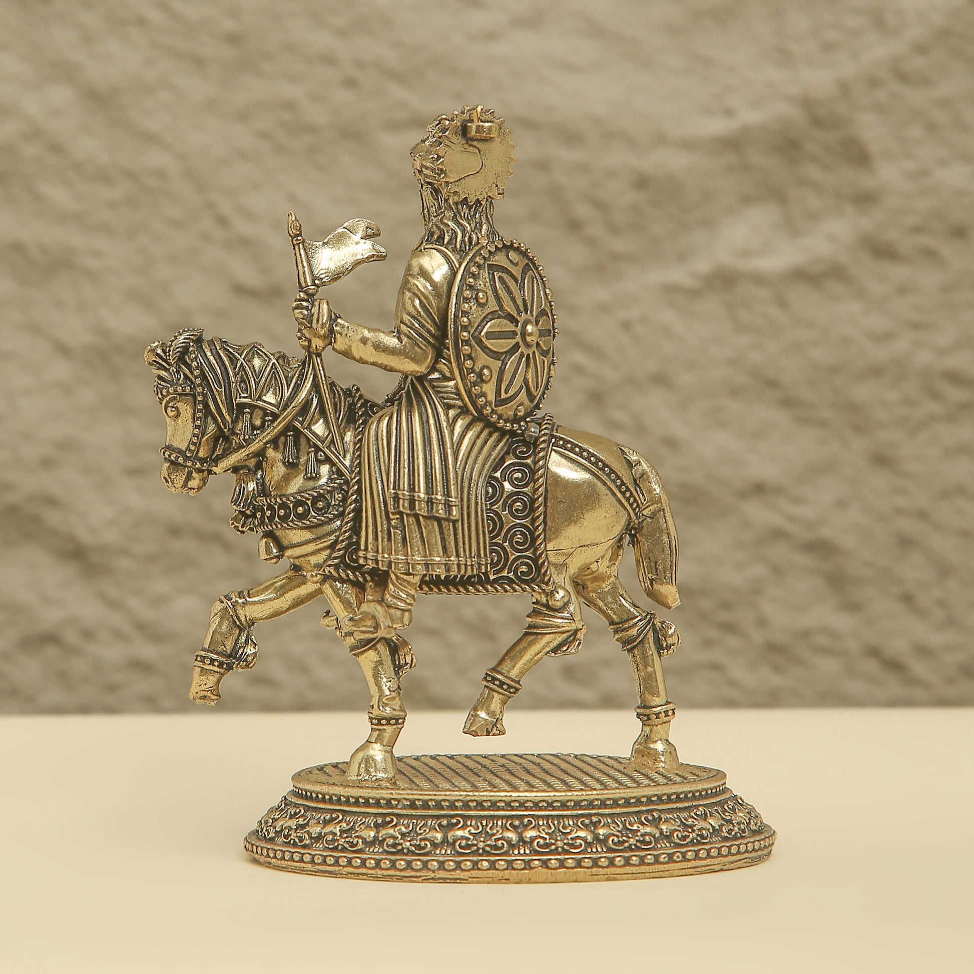 Bronze statue of a warrior on horseback with intricate details against a neutral background