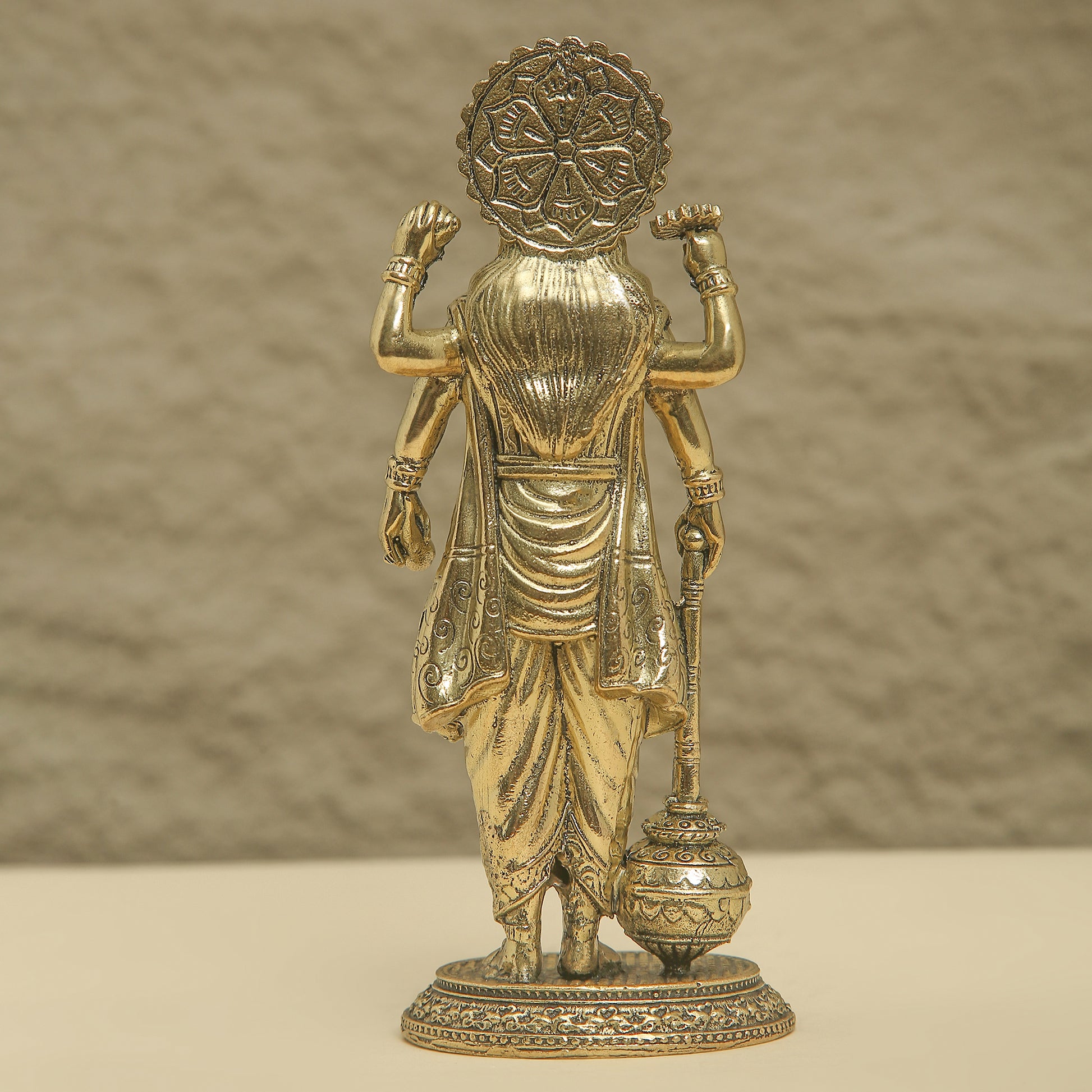 Gold-colored statue of a deity on a beige background
