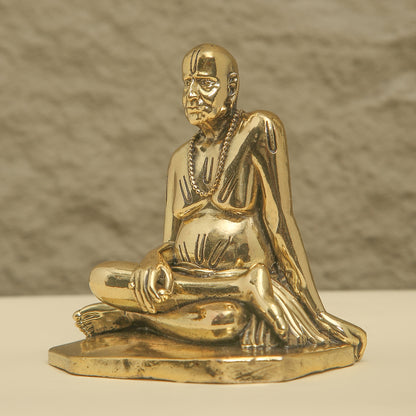 Gold statue of a seated figure on a beige background