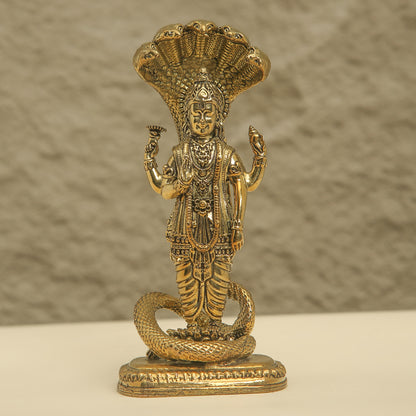 Brass statue of a deity with a snake on a beige background