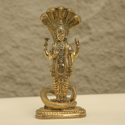 Brass statue of a deity with a snake on a beige background