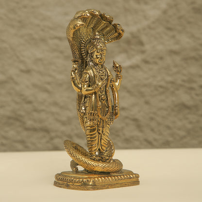 Gold-colored statue of a deity with a snake on a textured background