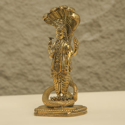 Gold-colored statue of a deity with intricate details on a textured background
