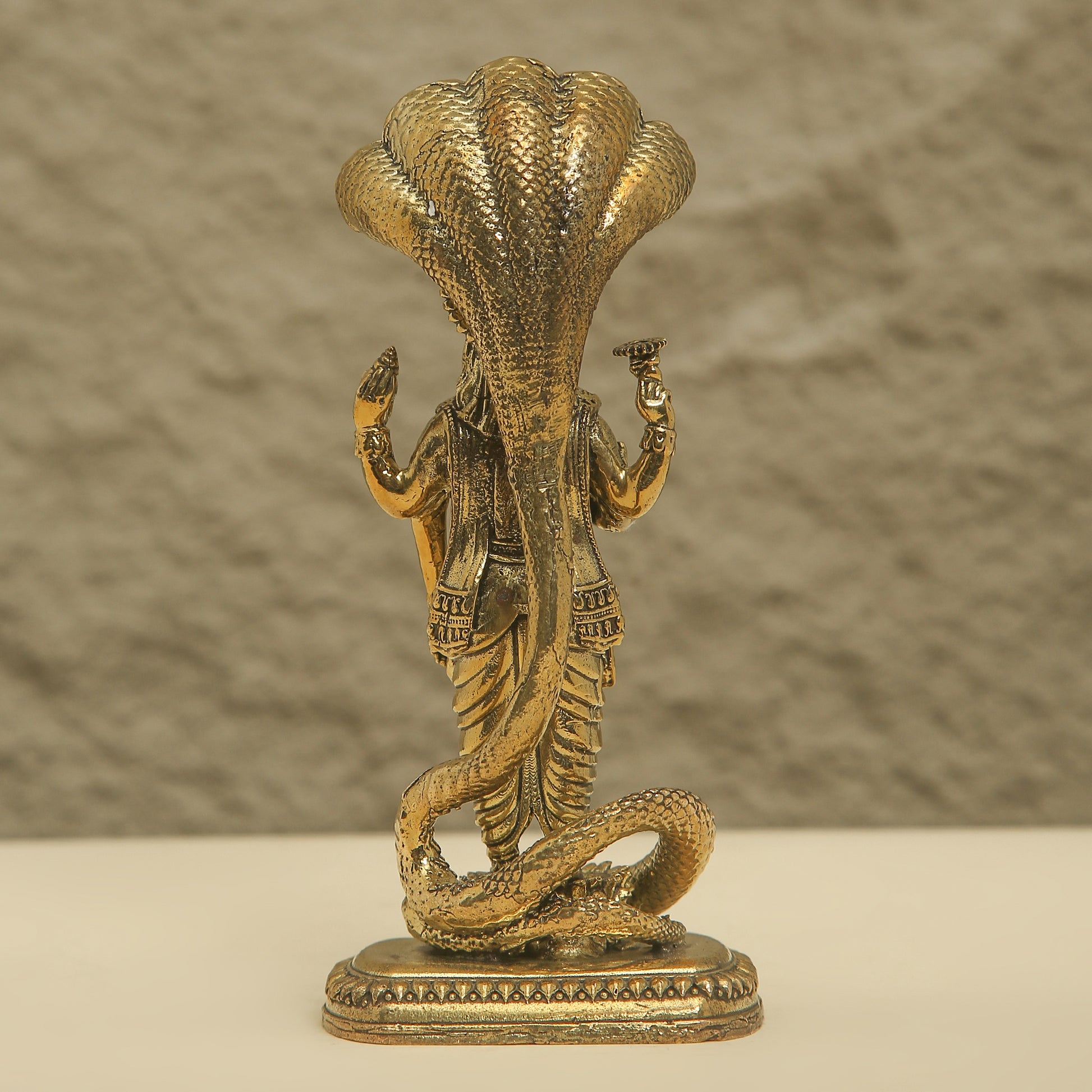 Bronze statue of a cobra with a person inside on a beige background