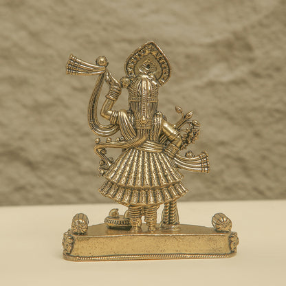 Gold-colored figurine of a deity on a textured beige background