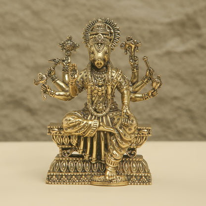 Gold-colored statue of a deity with multiple arms on a beige background