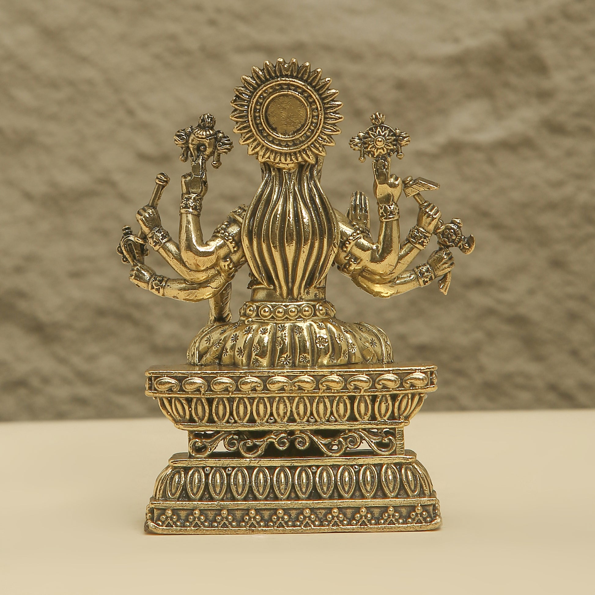 Decorative brass statue with intricate designs on a neutral background