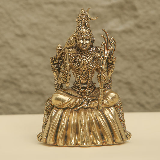 Gold-colored statue of a seated figure with intricate details on a neutral background