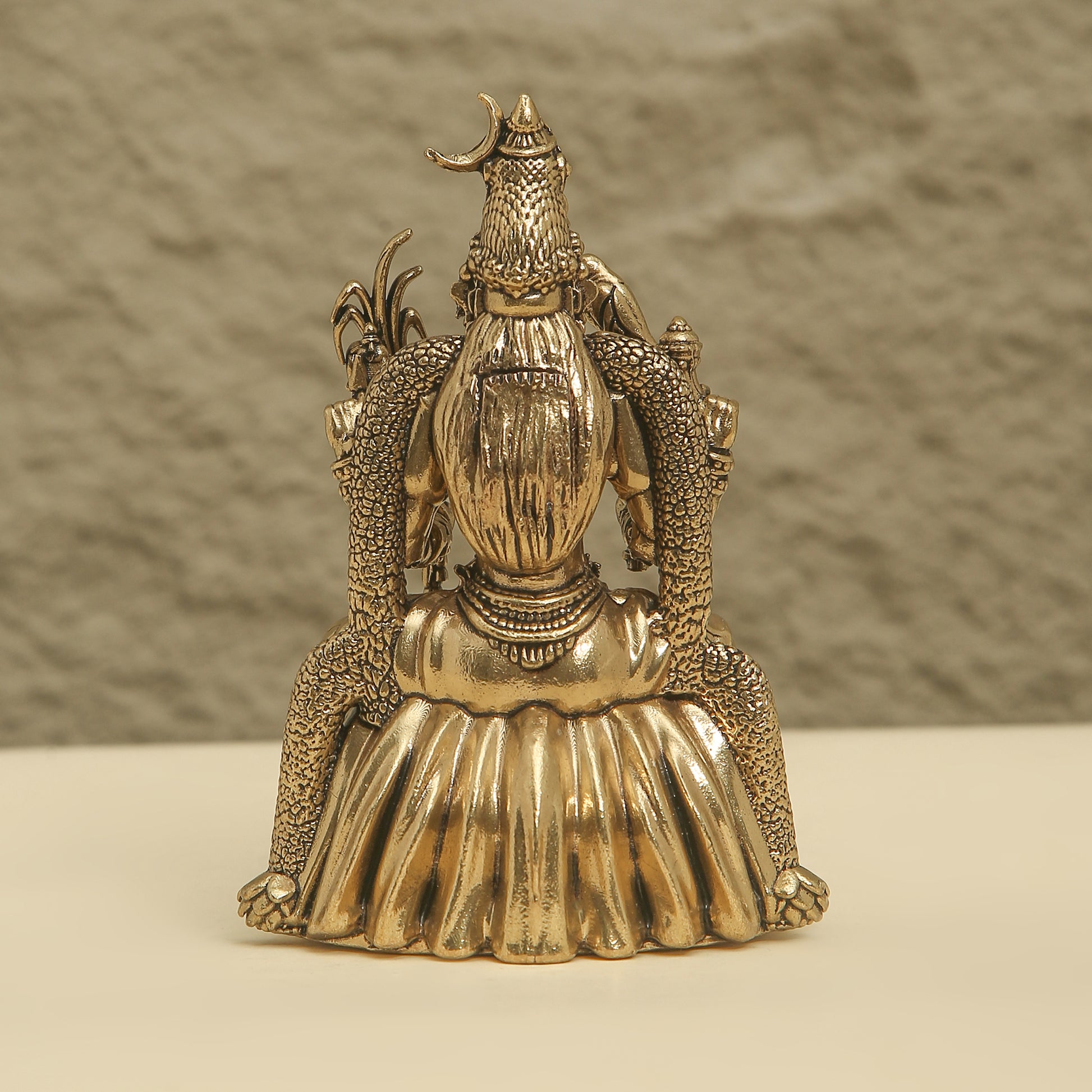 Gold-colored decorative object with intricate design on a neutral background
