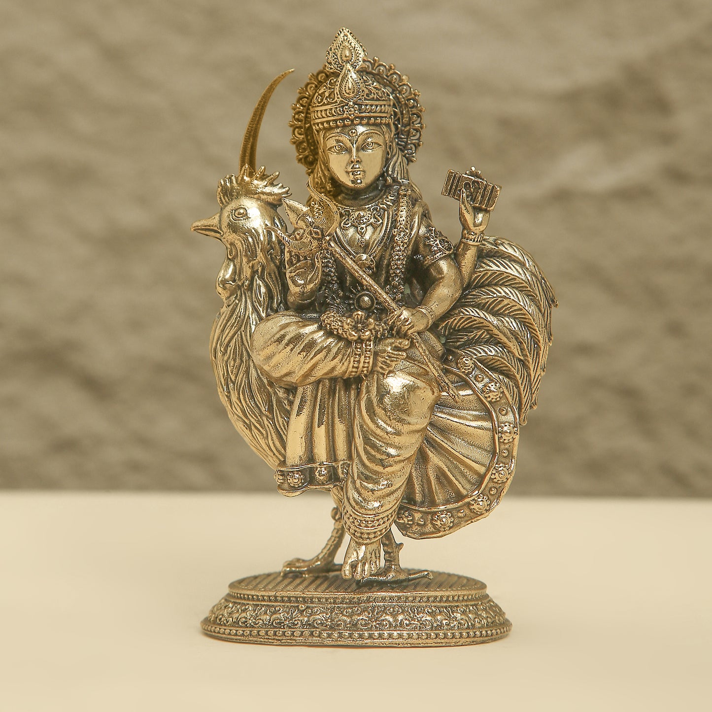 Bronze statue of a deity with a rooster on a beige background