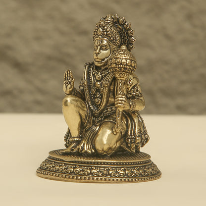 Bronze statue of a seated figure with intricate details on a beige background