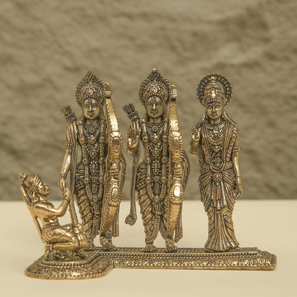 Decorative bronze figurine of three standing figures and one kneeling figure on a textured background