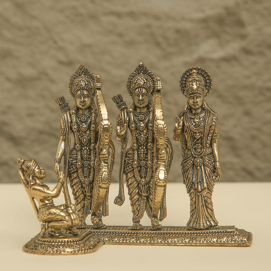 Decorative bronze figurine of three standing figures and one kneeling figure on a textured background