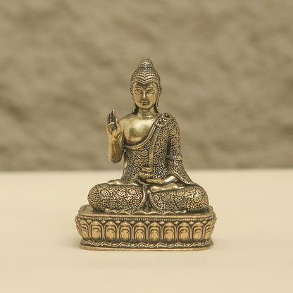 Bronze statue of a seated Buddha on a beige background
