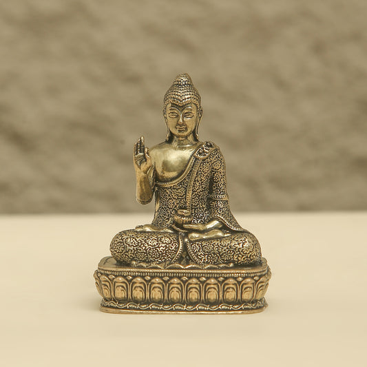 Bronze statue of a seated Buddha on a beige background