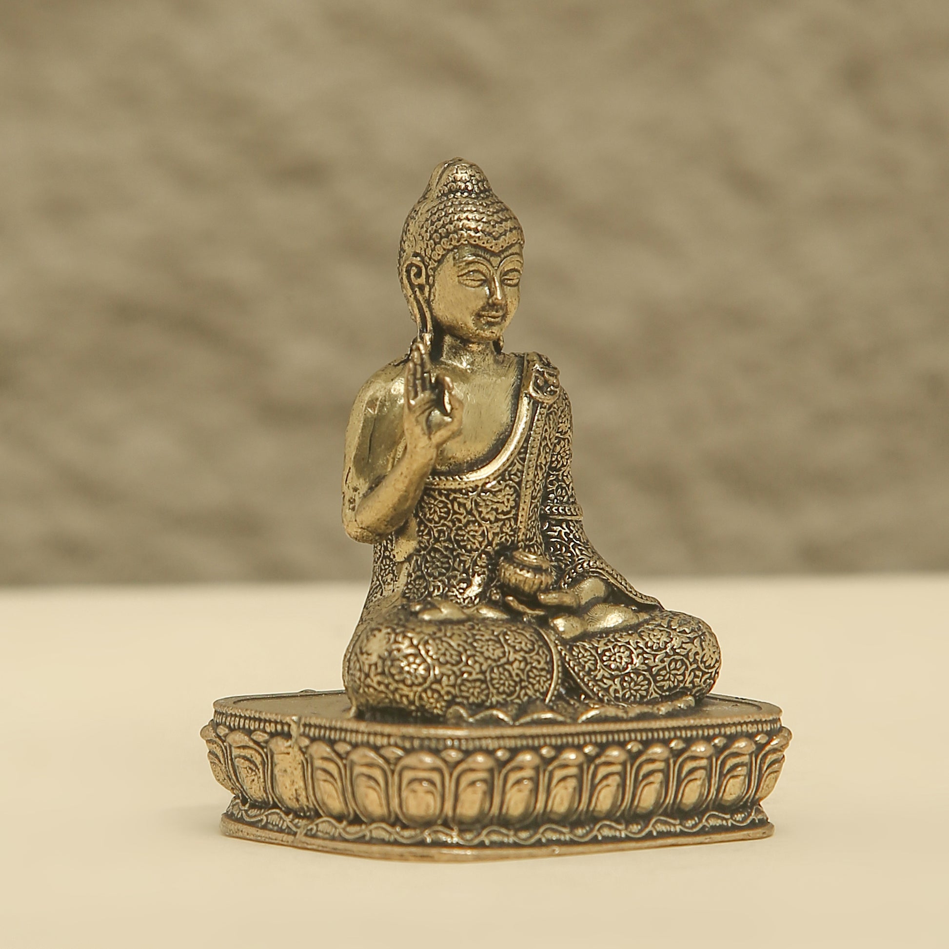 Bronze statue of a seated Buddha on a textured surface