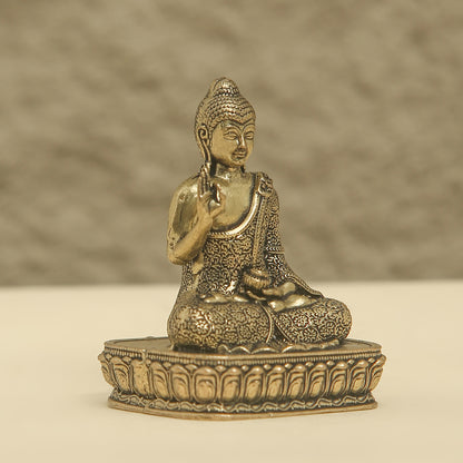Bronze statue of a seated Buddha on a textured surface