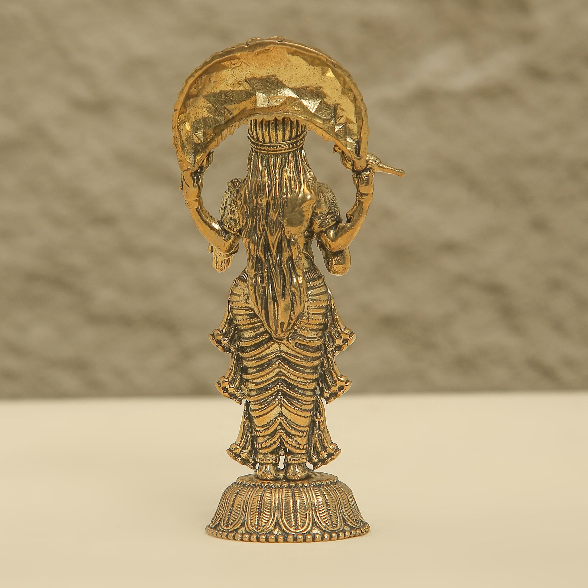 Gold-colored statue of a deity on a beige background