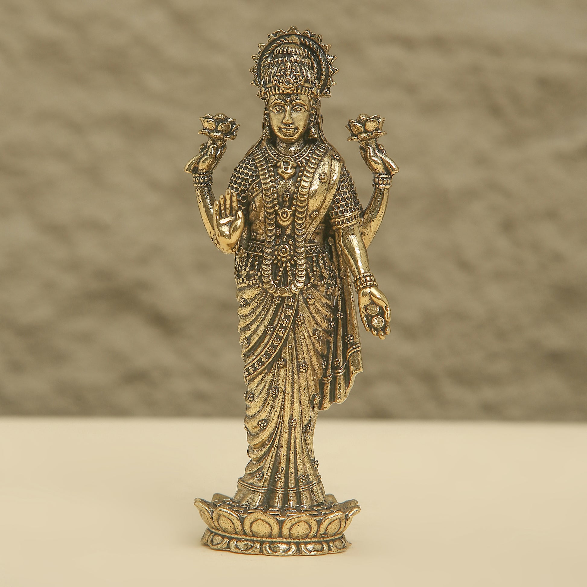 Bronze statue of a deity with intricate details on a beige background