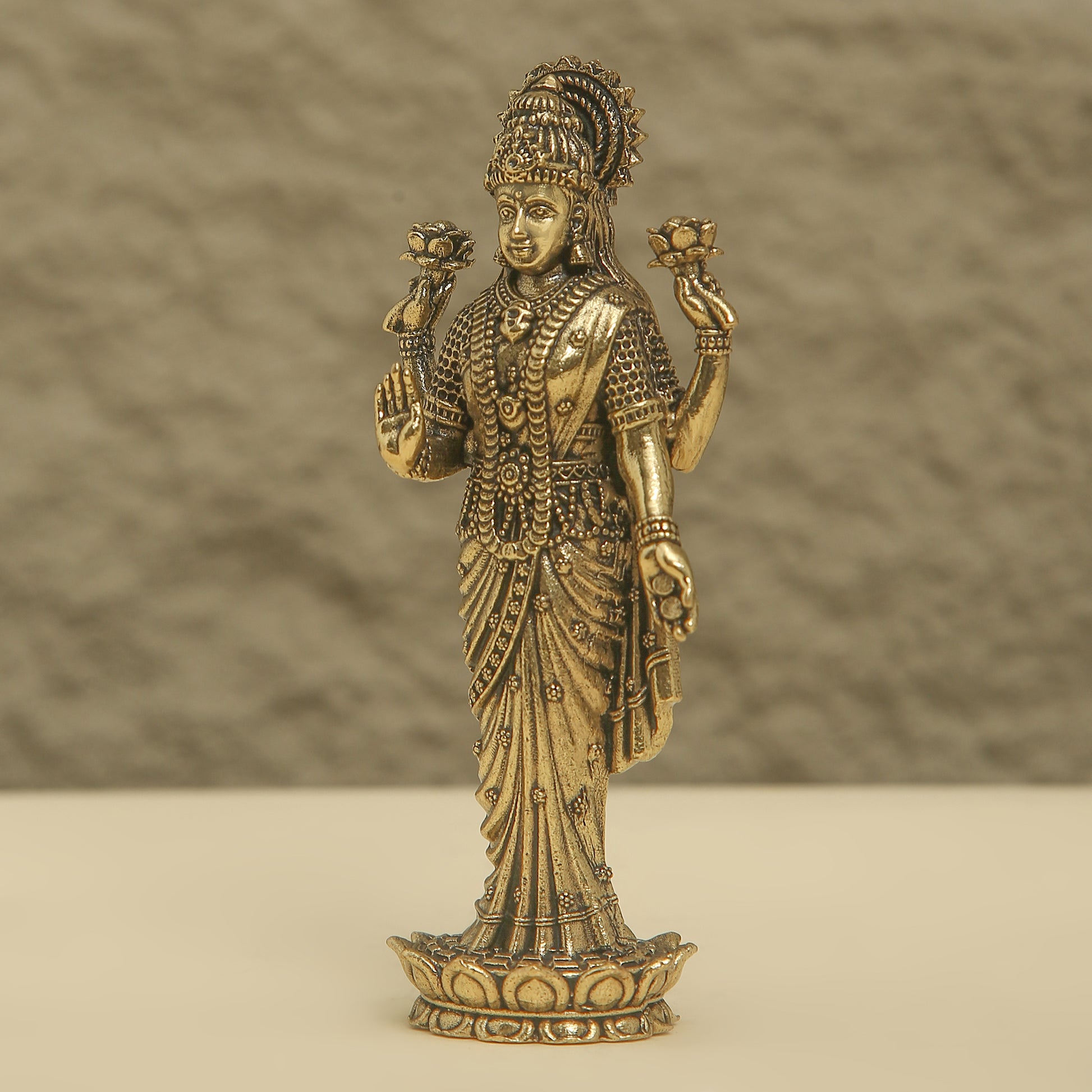 Bronze statue of a deity with intricate details on a beige background