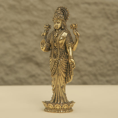 Bronze statue of a deity with intricate details on a beige background