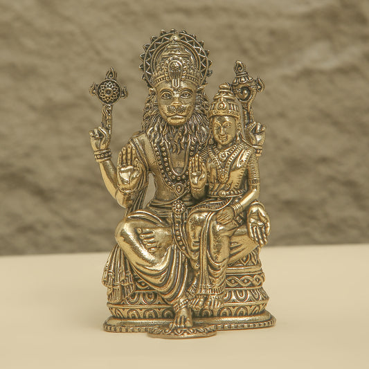 Bronze statue of a seated figure with another figure on its lap against a textured brown background