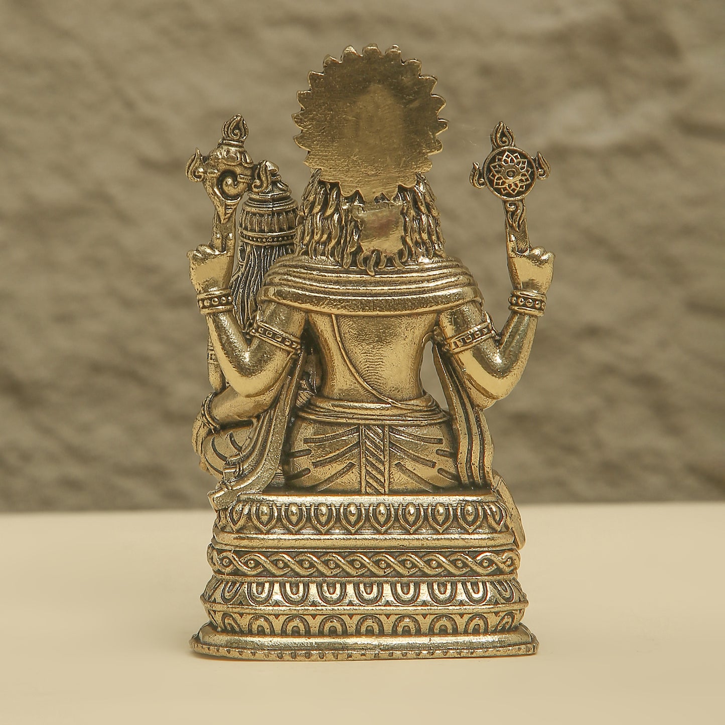 Bronze statue of a seated figure with intricate details on a textured background