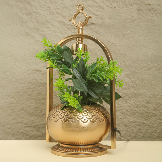 Decorative gold lantern with green plants against a neutral background